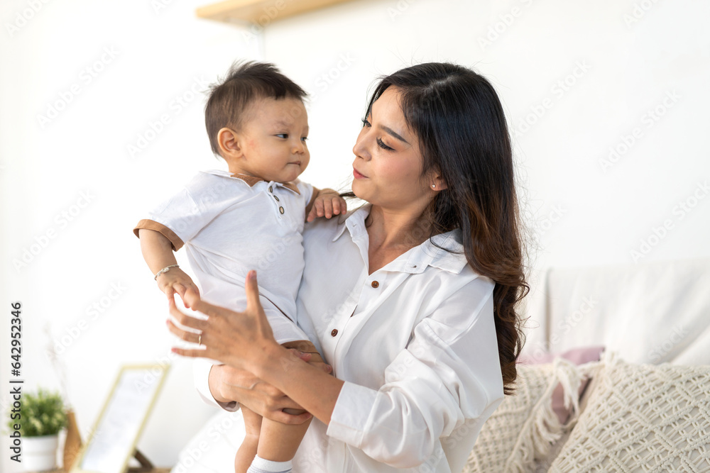 Portrait of enjoy happy love family asian mother playing with adorable little asian baby.Mom touching with cute son moments good time in a white bedroom.Love of family concept Portrait of enjoy happy love family asian mother playing with adorable little asian baby.Mom touching with cute son moments good time in a white bedroom.Love of family concept