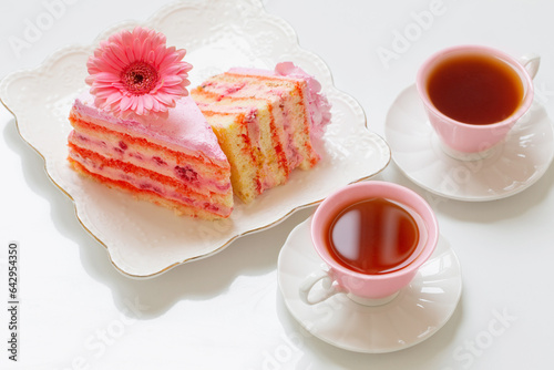 two cups of tea with pink cake on white table