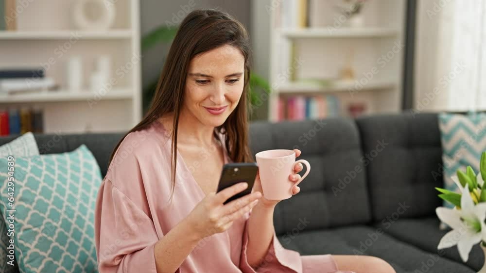 Young beautiful hispanic woman using smartphone drinking coffee at home Young beautiful hispanic woman using smartphone drinking coffee at home