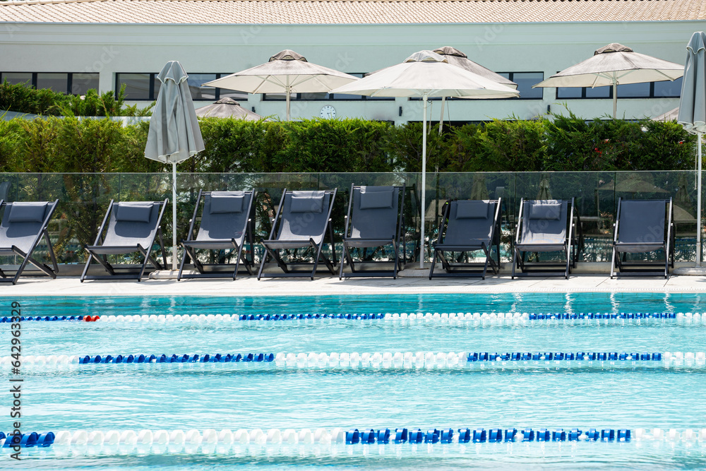 Swimming pool with arranged empty sun loungers.