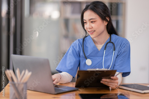 Portrait of Young Asian smiling female nurse working on laptop in private clinic, Positive emotional and good moment.Health Care Concept.