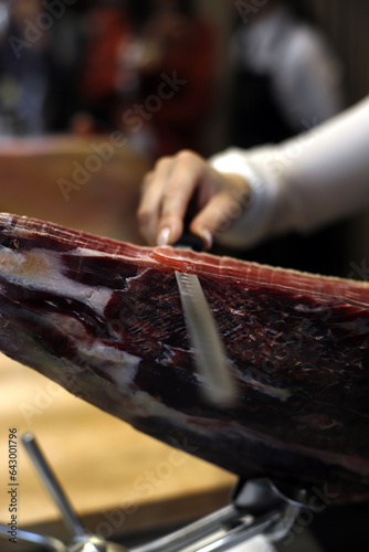 expert cutting iberian ham with long knife