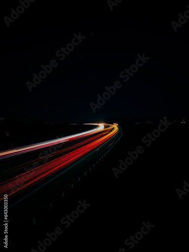 Long exposure of night city. Car motion trails on road. Speed light streaks background with blurred fast moving light effect