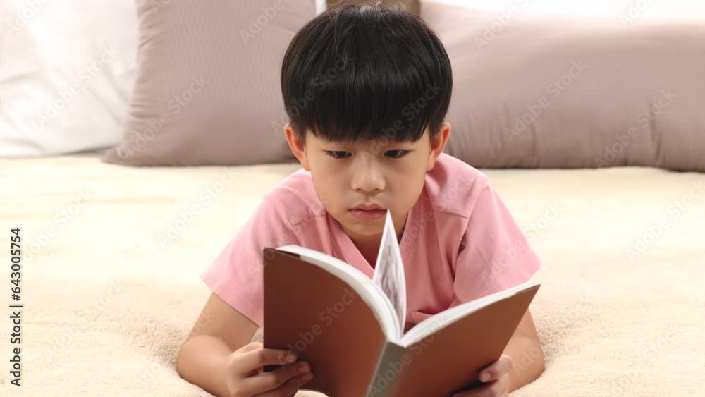 Asian handsome boy reading favorite book while lying down on bed at home, happy little kid spend time free to their advantage. Son enjoying reading manga new story. staying at home in self isolation. Asian handsome boy reading favorite book while lying down on bed at home, happy little kid spend time free to their advantage. Son enjoying reading manga new story. staying at home in self isolation.