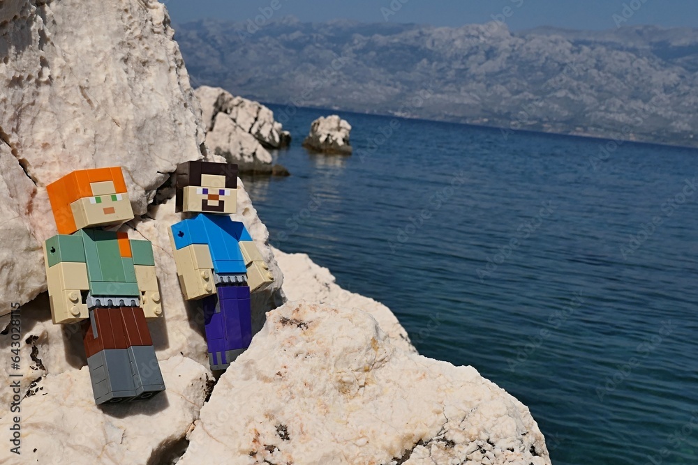 Obraz premium LEGO Minecraft main characters Alex and Steve sunbathing on rocks sunlit rocky beach of Razanovac near Razanac town, northern Dalmatia.