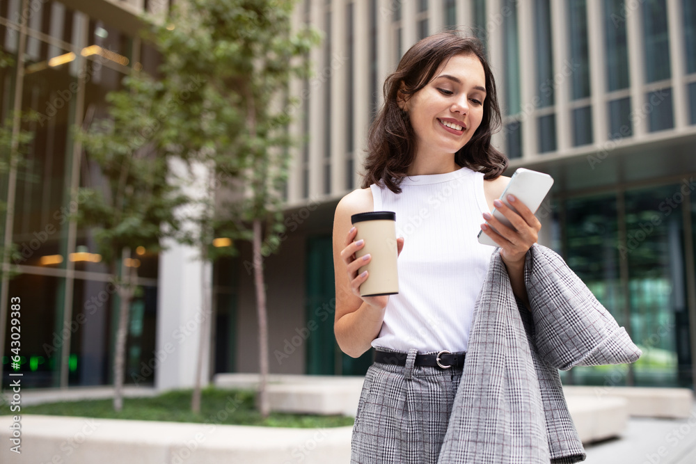 Fototapeta premium Smiling Young Businesswoman Texting On Smartphone Outdoor In City Area