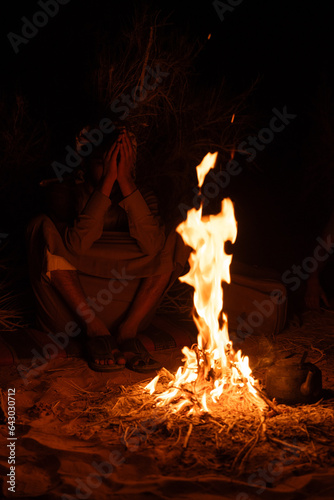 Unrecognizable person next to a bonfire in the dark