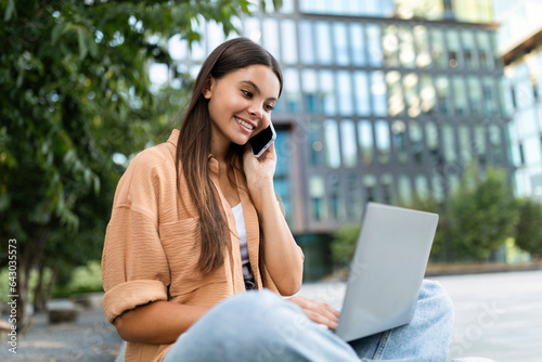 Positive young woman freelancer working on laptop outdoor