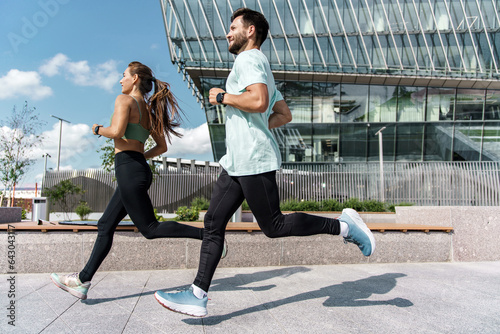 Runners are a young couple training on the street. Athletes are friends of running exercises. A fitness instructor and a woman training in sportswear and sneakers.
