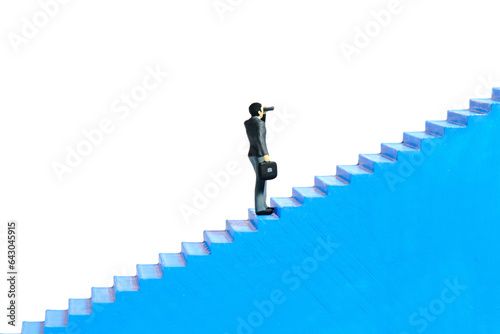 Miniature tiny people toys photography. Businessman using binocular telescope walking up the stair. Isolated on a white background