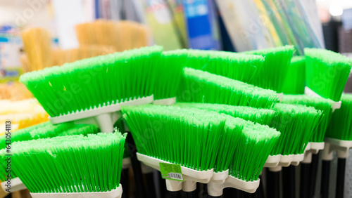 Plastic brushes for cleaning premises. Assortment of multi-colored brooms in the store. Close-up