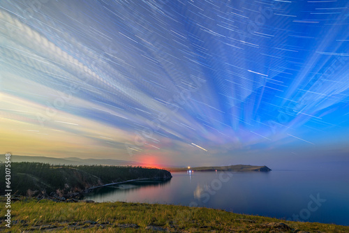 Russia, Lake Baikal, Olkhon Island, Clouds and stars on a moonlit night over Small Sea Bay. Long tracks from the stars, echo through the clouds photo