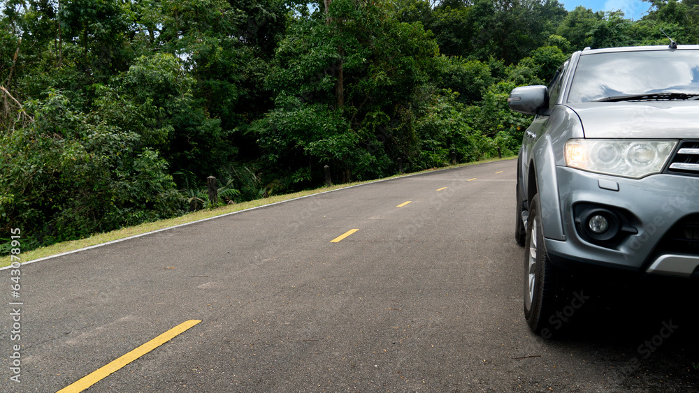 Front of grey car driving on asphalt road with yellow line. Beside wtih green grass and forest. Travel trip of reservoir of Khiri Than Chanthaburi. Front of grey car driving on asphalt road with yellow line. Beside wtih green grass and forest. Travel trip of reservoir of Khiri Than Chanthaburi.