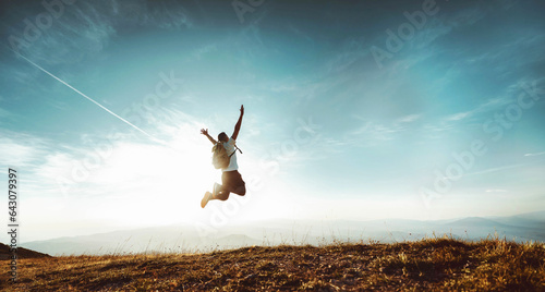 Fotografia Happy man with arms up jumping on the top of the mountain - Successful hiker cel