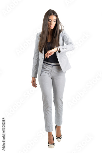 Young businesswoman checking hand watch walking forward in the rush. Full body isolated on transparent background.
