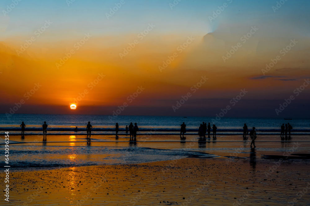 Obraz premium The silhouette of people engaged in activities, enjoying the sunset on Kuta Beach in Bali.