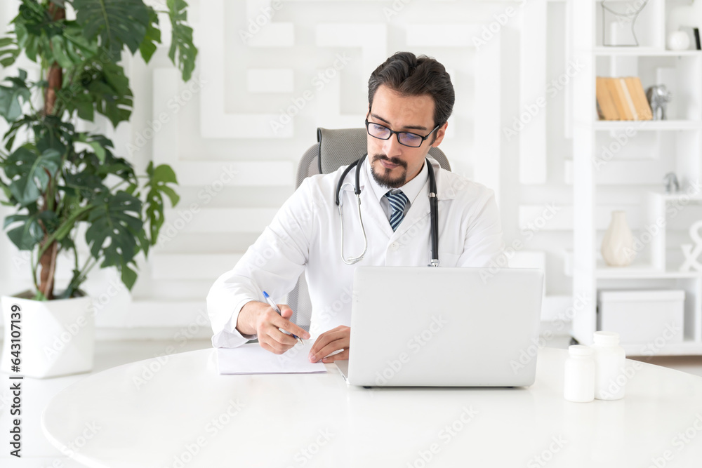 Young handsome male doctor working in the office of modern clinic Young handsome male doctor working in the office of modern clinic