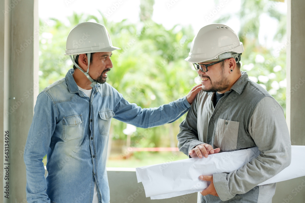 Bearded Indian engineer wearing helmet Standing to order work for foreman Follow plans in blueprint. Let workers speed up construction of houses in construction area. Cooperation of multiethnic people Bearded Indian engineer wearing helmet Standing to order work for foreman Follow plans in blueprint. Let workers speed up construction of houses in construction area. Cooperation of multiethnic people