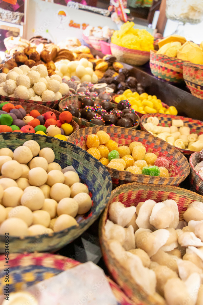 Dulces del corpus Christy acomodados en diagonal sobre unas canastillas depaja tejida multicolorica, dulces de coco mazapan,bombones tradicionales de la ciudad de Cuenca Ecuador