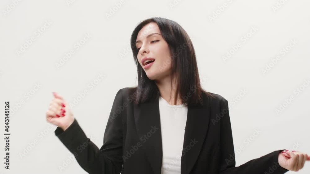 A business woman in a business suit is dancing with an inspired expression on her face. Active young woman having fun on a light background. A business woman in a business suit is dancing with an inspired expression on her face. Active young woman having fun on a light background.