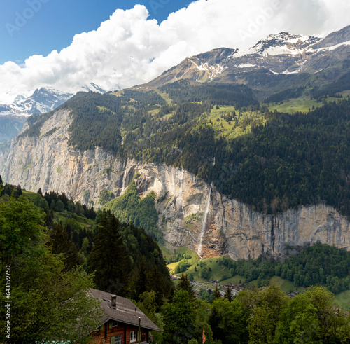 Waterrfall in the Swiss Alps in Switzerland in the Summer With Mountains Peaking Through the Clouds in the Background  photo