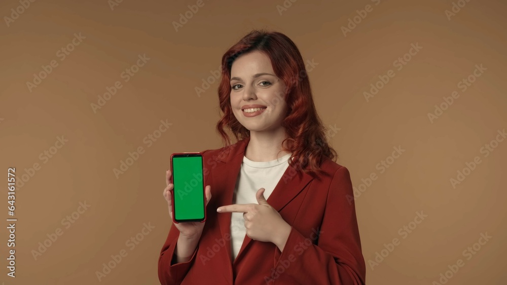 Medium isolated shot of a young woman smiling at the camera and pointing at the phone with advertising area, workspace mock up. Medium isolated shot of a young woman smiling at the camera and pointing at the phone with advertising area, workspace mock up.