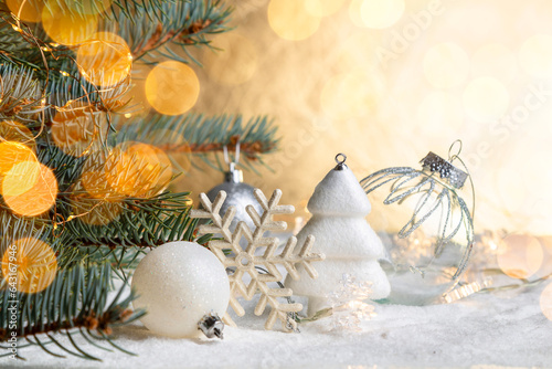 Christmas decorations on a snowy table with fir branches and glowing garlands. Copy space