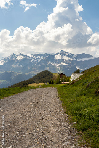 Road Leading Up the Swiss Alps in Switzerland in the Summer with Mountains Peaking Through Clouds in the Background