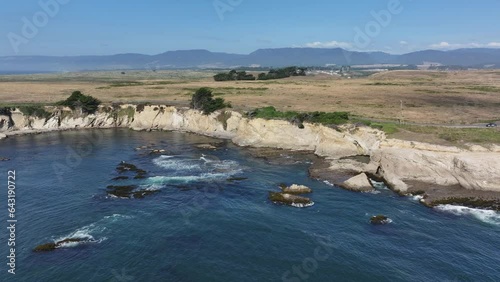 Aerial northern California rocky ocean cliff slide 2. Pacific Ocean coastal shoreline highway. California State Route 1, Mendocino County. Blue water, sand, rocky islands and cliffs. Seascape. photo