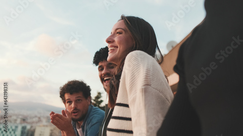 Close-up of young people, guys and girls friends standing hugging each other on the balcony looking at the beautiful views