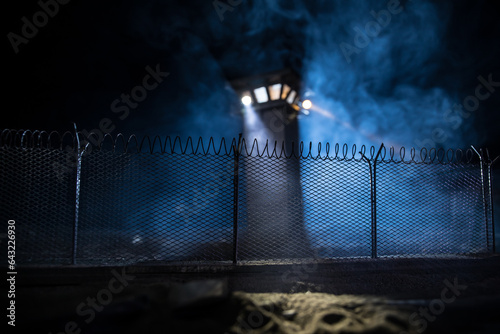 Canvastavla Old prison watchtower protected by wire of prison fence at night