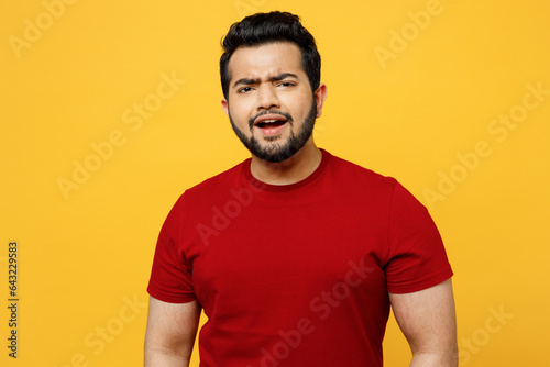 Young disappointed displeased dissatisfied sad Indian man he wearing red t-shirt casual clothes lok camera with sad face emotion isolated on plain yellow orange background studio. Lifestyle concept.