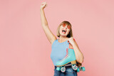 Overjoyed elderly blonde woman 50s years old she wearing blue undershirt casual clothes do winner gesture hold roller bladers isolated on plain pastel light pink background studio. Lifestyle concept.