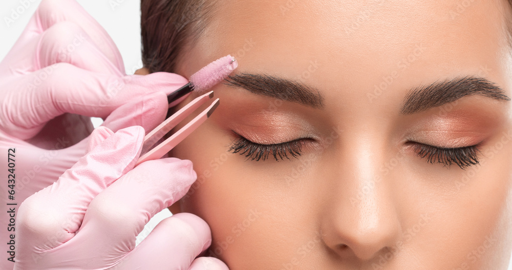 Makeup artist combs  and plucks eyebrows after dyeing in a beauty salon.Professional makeup and cosmetology skin care.