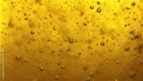 Small bubbles in the yellow liquid slowly rise to the top. beer or gel, shampoo or oil