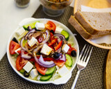 Traditional Greek salad with fresh vegetables, feta cheese and black olives served on white plate.