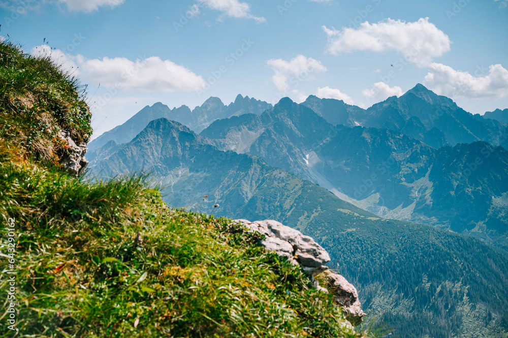 High Tatras from the Belianske Tatras, where emerald meadows meet the towering peaks, all beneath a sky of boundless blue