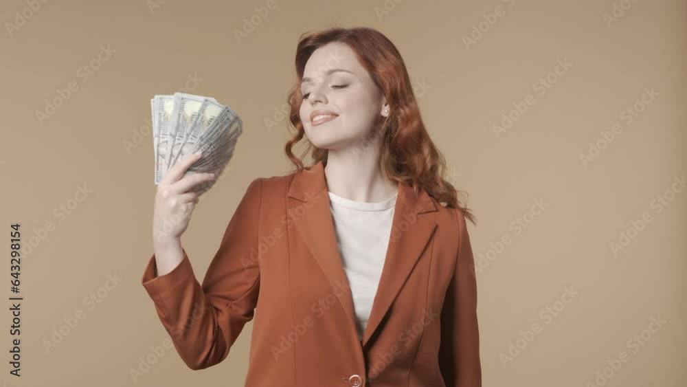 Medium isolated video of a young woman blowing herself with bills using them like a fan and smiling. Money and cash topic. HDR BT2020 HLG Material. Medium isolated video of a young woman blowing herself with bills using them like a fan and smiling. Money and cash topic. HDR BT2020 HLG Material.