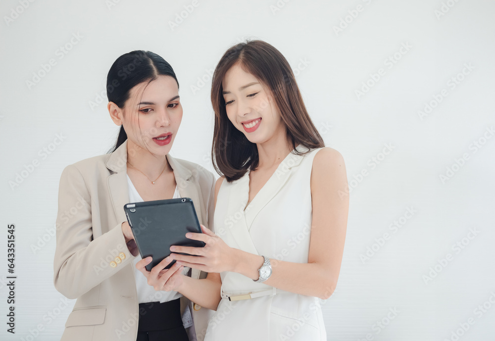 Portrait business team two woman pretty girl cute and Asian group standing on wall white looking talk hand holding tablet with in agreement ready for happy job working online sale inside home office Portrait business team two woman pretty girl cute and Asian group standing on wall white looking talk hand holding tablet with in agreement ready for happy job working online sale inside home office
