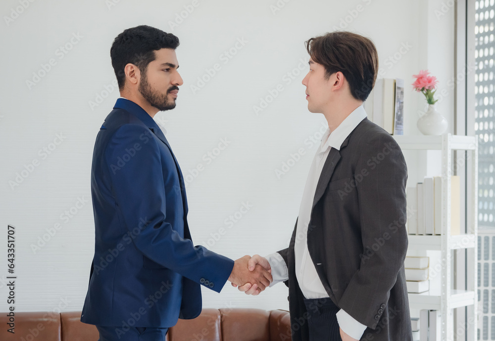 Portrait business manager team man handsome smart Asian two people group standing on wall white looking shake hand within the agreement ready for happy working online creative sale inside home office