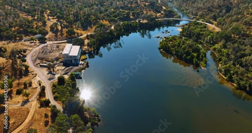 Beautiful scenery of the lake reflecting bright sun. Amazing panorama of Sierra National Forest, California, USA from aerial perspective.