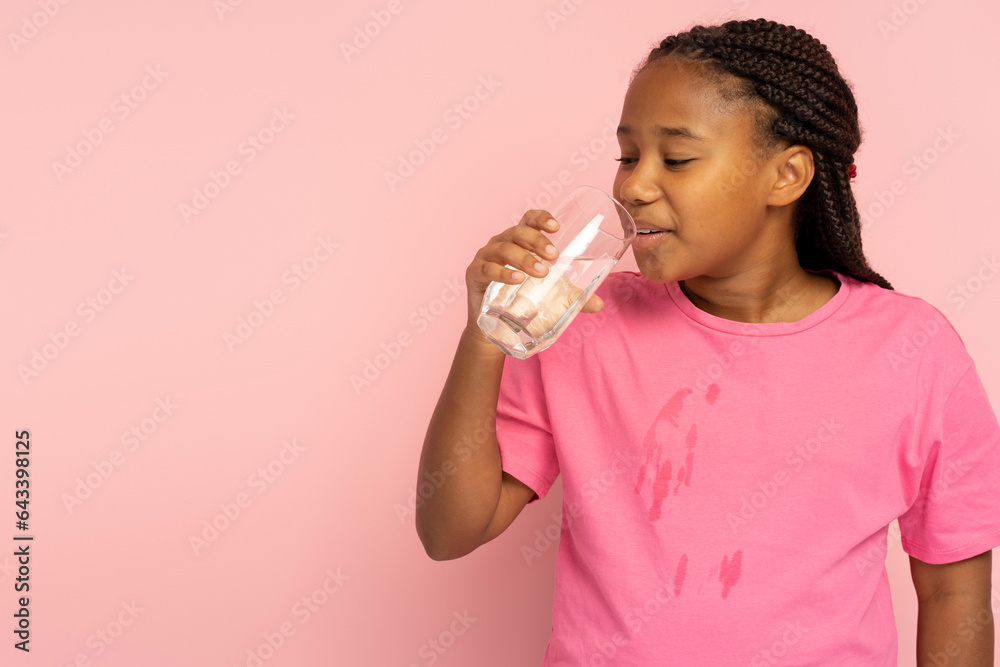 Beautiful positive African girl with stylish hairstyle drinking water from glass Beautiful positive African girl with stylish hairstyle drinking water from glass