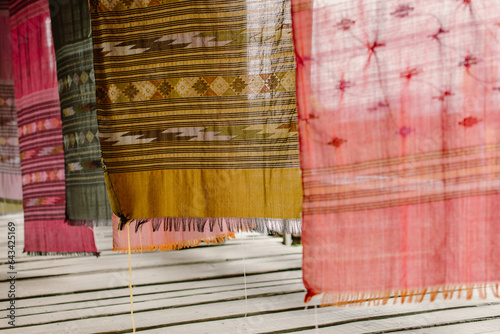 Native woven fabrics of northern Thailand. Colorful traditional fabrics on wooden bridge at Tai Lue coffee shop. Vertical image.
 photo