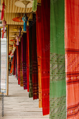Native woven fabrics of northern Thailand. Colorful traditional fabrics on wooden bridge at Tai Lue coffee shop. Vertical image.
