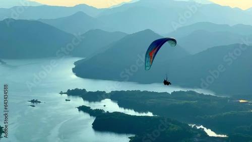 a person who paraglides on high mountains overlooking the lake
 photo