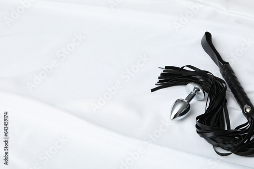Flogger and butt plug on a light background.