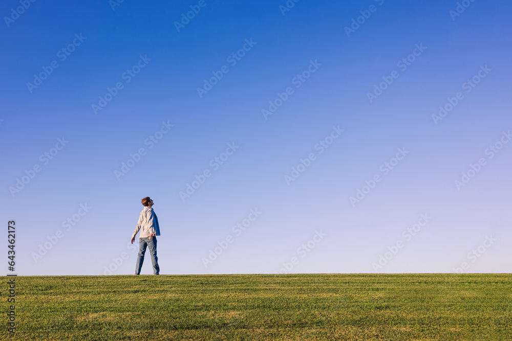 Happy man enjoying fresh air and nature, standing on the horizon on the green grass Happy man enjoying fresh air and nature, standing on the horizon on the green grass