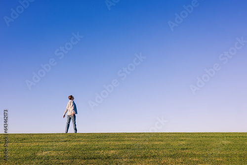 Happy man enjoying fresh air and nature, standing on the horizon on the green grass