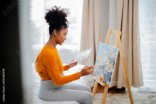 African American pregnany painting in bed room, pregnant girl doing hobby for relaxing with smile and appreciate. photo