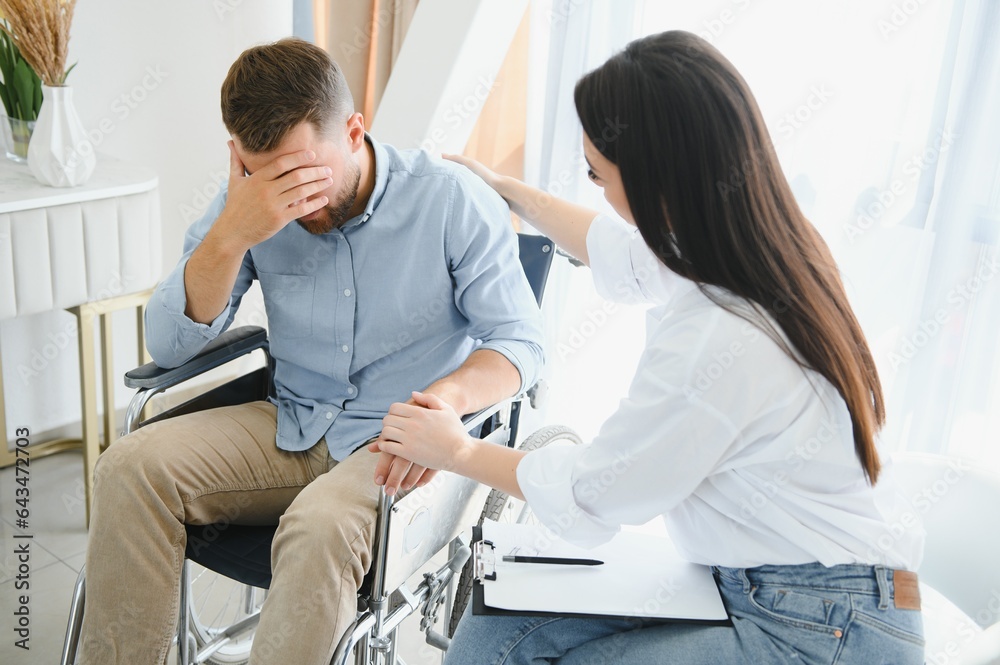 Fototapeta premium Young disabled man talking to female psychologist at home
